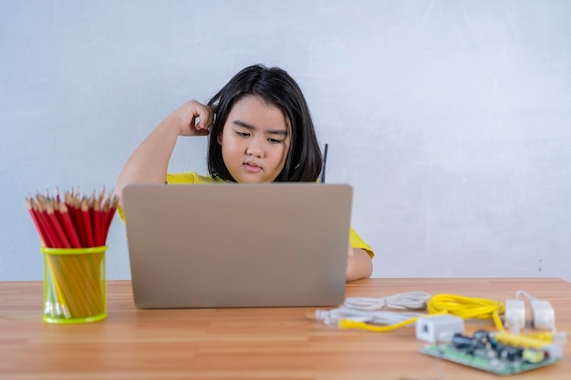 Les filles asiatiques utilisent un ordinateur portable pour assembler une simple carte de circuit imprimé L'éducation STEM pour les enfants Elle est confuse à l'idée d'étudier