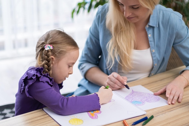 Filles assises avec un enseignant en classe apprenant à dessiner et à peindre une école d'art pour enfants