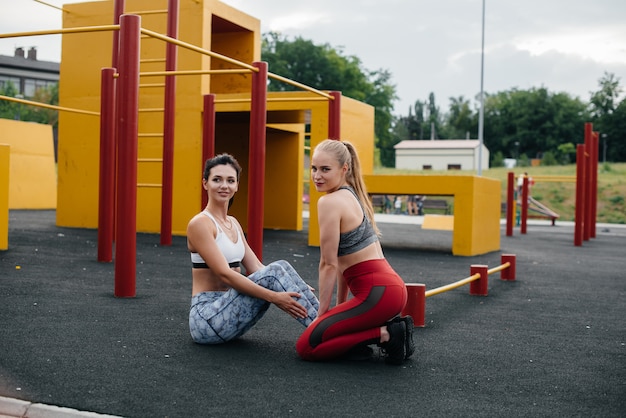 Des filles athlétiques et sexy effectuent des exercices abdominaux en plein air. Fitness, mode de vie sain