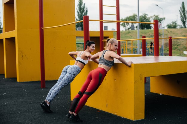 Photo les filles athlétiques et sexy font des push-ups à l'extérieur de manière synchrone. fitness, mode de vie sain