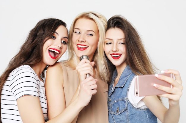 Filles de beauté avec un microphone chantant et s'amusant ensemble