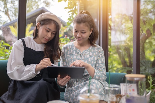 Les filles boivent du café se détendent au café Freelancer communiquent sur le projet les filles achètent en ligne sur une tablette wifiLes étudiants étudient sur InternetProcessus métier de travail