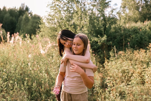 Filles en cueillette de fleurs sauvages à la lumière du coucher du soleil, marchant dans la prairie d'été. Moment authentique atmosphérique. Ramasser des fleurs à la main dans la campagne. Ralenti rural