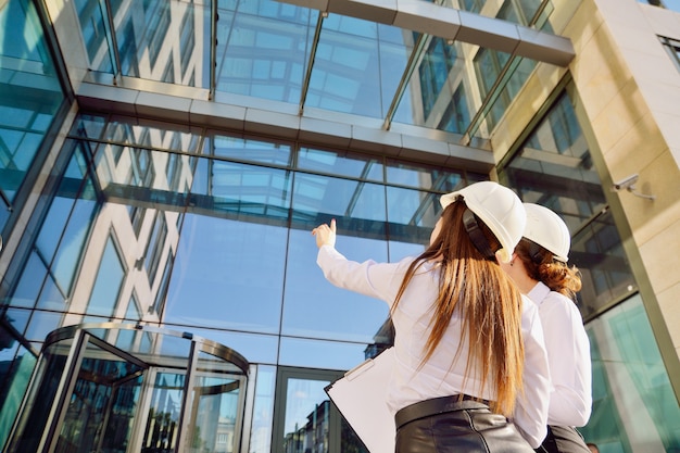 Photo filles dans la construction de casques blancs avec des tablettes dans les mains