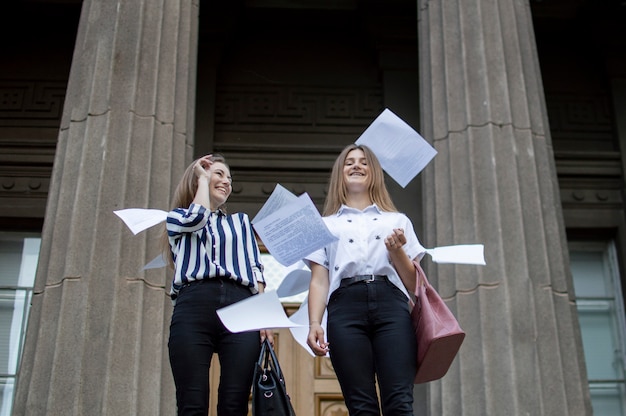 Filles debout et jetant des feuilles de papier