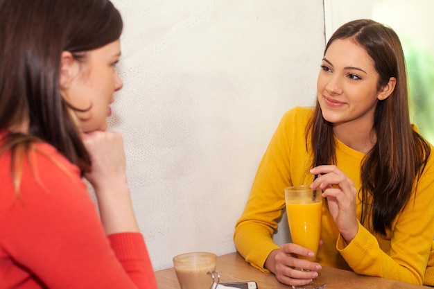 filles discutant au café buvant du jus d'orange interrogé