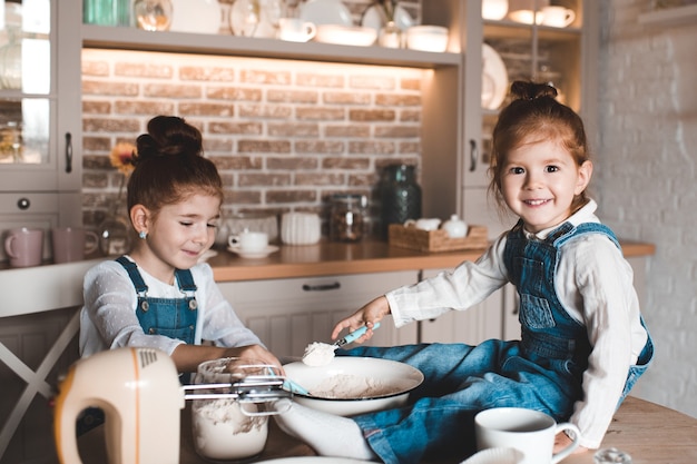 Filles drôles d'enfant faisant cuire le gâteau avec de la farine dans la cuisine