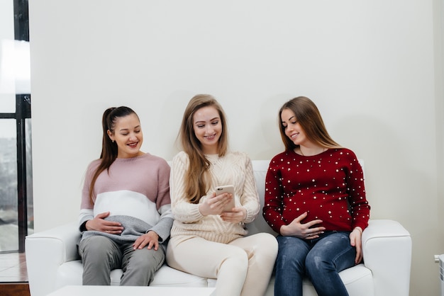 Les filles enceintes s'assoient sur le canapé et s'amusent à discuter entre elles. Grossesse et prendre soin de l'avenir de l'enfant