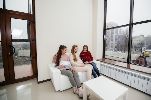 Les filles enceintes s'assoient sur le canapé et s'amusent à discuter entre elles