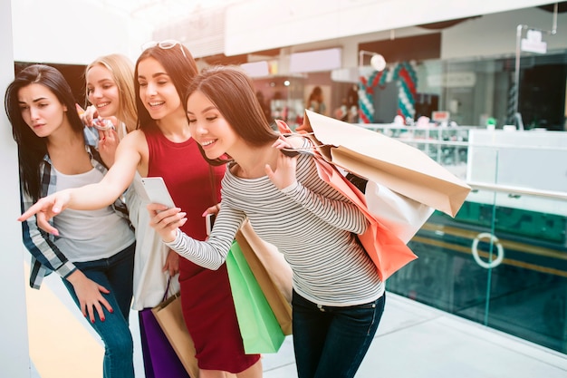 Des filles gaies et heureuses se tiennent l'une après l'autre et regardent vers le bas