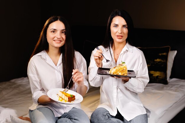 Filles gaies mangeant des gâteaux assis sur la chambre dans l'appartement