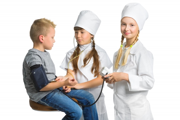 Des filles habillées comme des médecins mesurant la pression artérielle d'un garçon