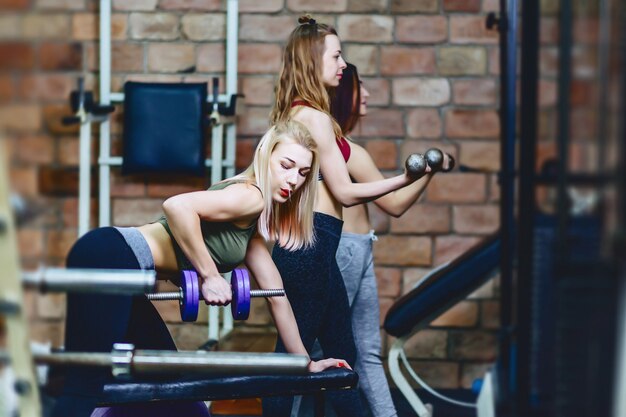 Filles avec des haltères dans la salle de gym