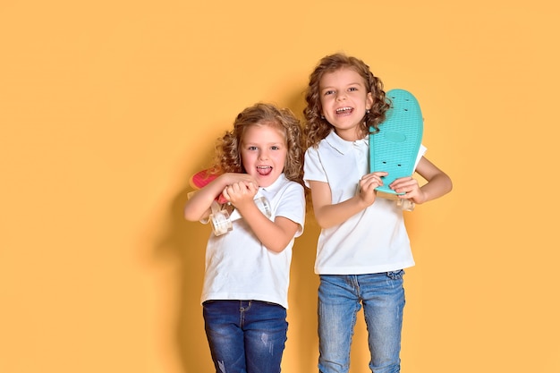 Filles heureuses aux cheveux bouclés s'amuser avec des planches de penny