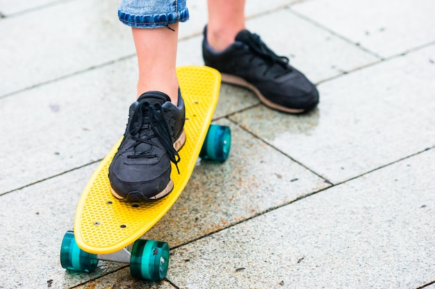 Filles hipster avec planche à roulettes à l'extérieur sous la pluie. Gros plan skatebord. Femme sportive active s'amuser dans le skate park.