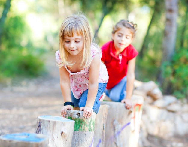 filles kid jouant sur des troncs dans la nature de la forêt