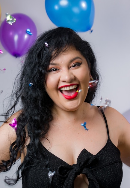 Filles latino-américaines posant et célébrant la nouvelle année avec des ballons et des confettis