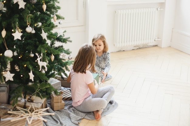 Filles à la maison à Noël avec arbre et cadeaux