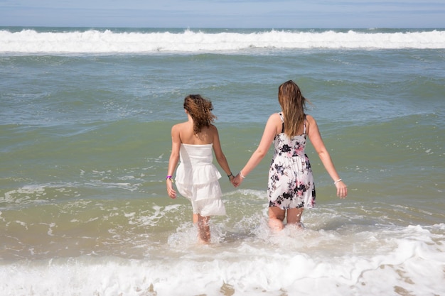 Filles à la mer Deux jeunes femmes entrent en mer vue arrière