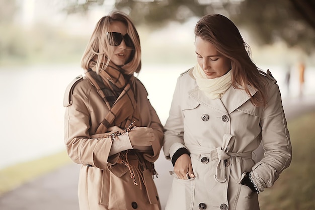 filles de parc de mode d'automne deux regardent / marchent dans un parc de la ville deux copines à la mode glamour dans un manteau