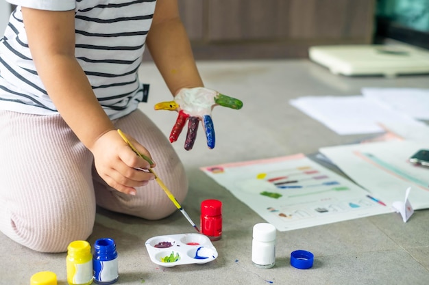 Les filles peignent sur leurs propres doigts pour rendre les devoirs d'art multicolores amusants