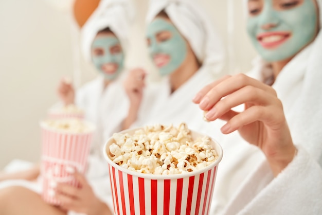 Filles en peignoirs mangeant du pop-corn.