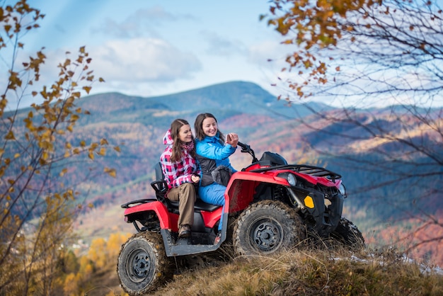 Des filles en quad rouge sur la colline font selfie au téléphone