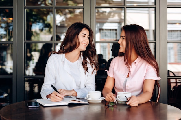 Les filles qui travaillent dans le café notent les thèses importantes dans le cahier