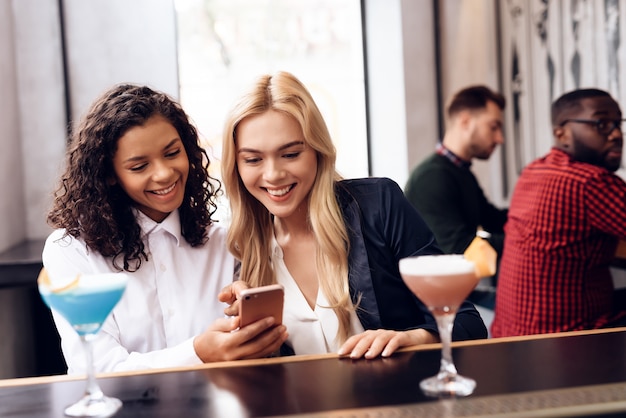 Les filles regardent l'écran d'un téléphone portable.