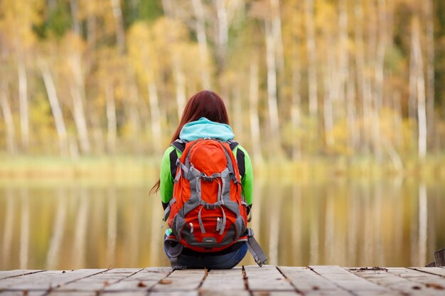 Filles avec sac à dos assis sur un pont en bois dans la forêt d'automne