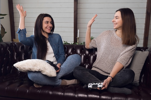 Les filles se donnent cinq, les joueuses jouent à la console de jeu et s'amusent à la maison. Photo de haute qualité