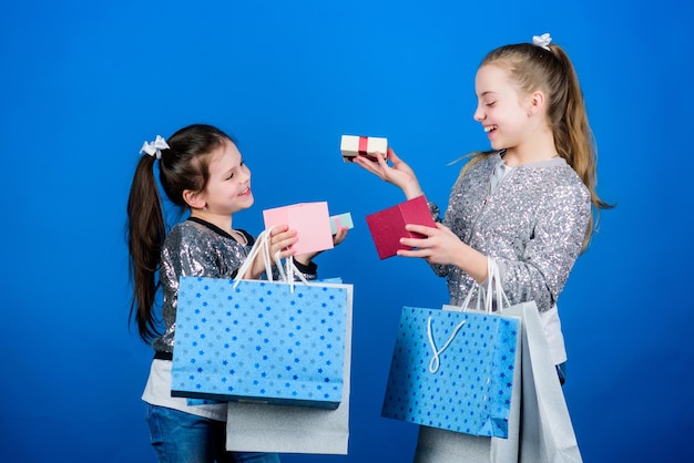 Filles soeurs amies avec des sacs à provisions fond bleu Chaque produit vous est livré Shopping et achat Vendredi noir Vente et remise Forfaits pour enfants Journée shopping Mode enfantine