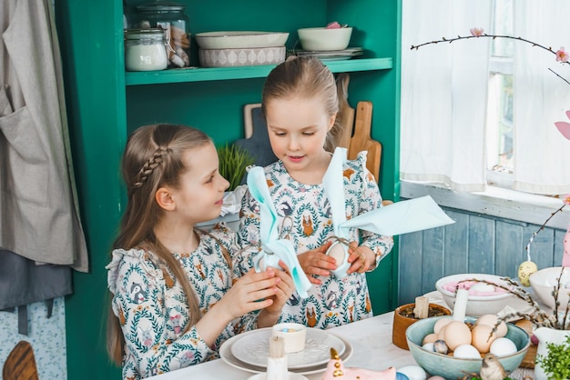 Filles soeurs à table avec décoration de Pâques Célébration dans la cuisine Paysage de table pour les vacances de Pâques à la maison