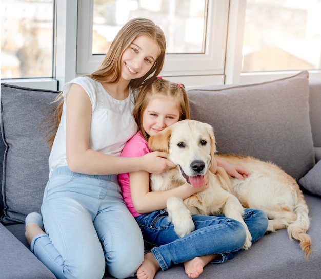 Filles souriantes câlins beau chien dans une pièce lumineuse