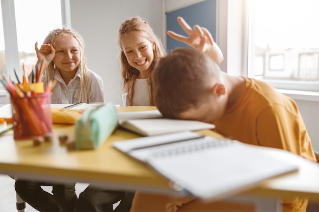 Filles souriantes plaisantant sur leur camarade de classe en classe