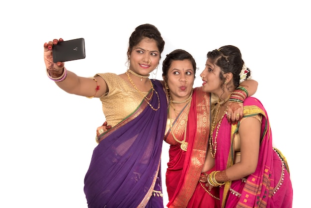 Filles traditionnelles indiennes prenant selfie avec smartphone sur blanc