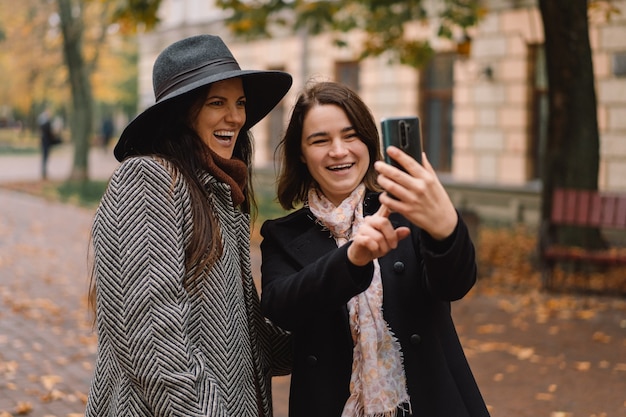 Filles utilisant le téléphone pour un appel vidéo à des amis dans le parc