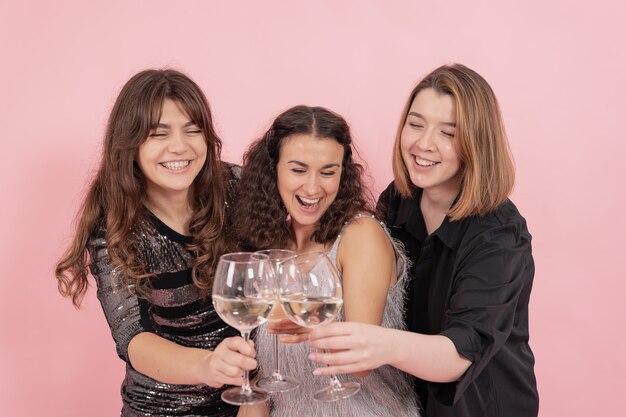 Les filles avec des verres de champagne s'amusent sur fond rose, fête, célébration.