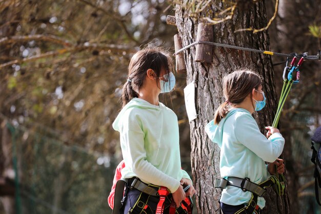 filles avec des vêtements de sport et un masque de protection contre les coronavirus sautant d'arbre en forêt d'installation de la canopée d'arbre en arrière-plan