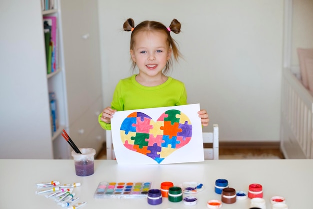 Une fillette de deux ans montre son dessin pour soutenir les enfants atteints du syndrome autistique