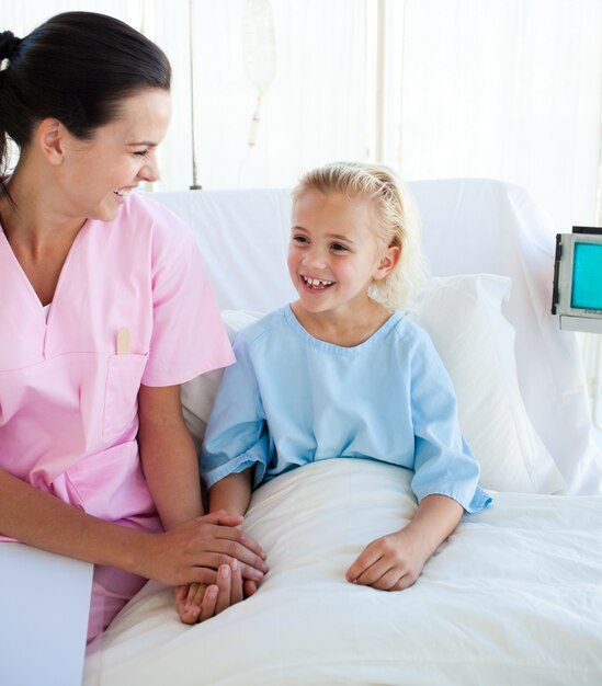 Fillette souriante assise sur un lit d&#39;hôpital avec son médecin