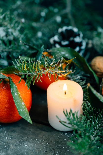 Film look image Composition de Noël avec des mandarines, des pommes de pin, des noix et des bougies sur fond en bois.