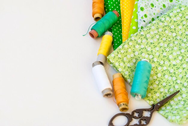 Des fils de bobine colorés avec des tissus sur fond blanc