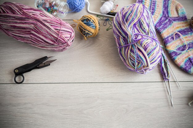 Fils colorés, aiguilles à tricoter et autres articles pour tricoter à la main sur une table en bois clair