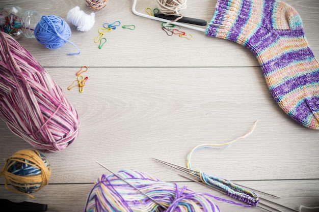 Fils colorés, aiguilles à tricoter et autres articles pour tricoter à la main sur une table en bois clair