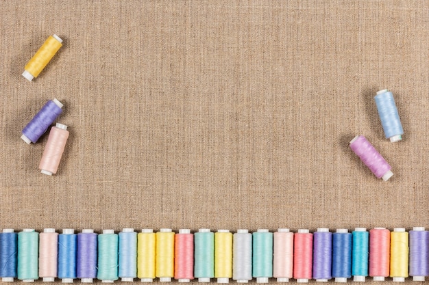 Fils à coudre colorés sur tissu de lin naturel avec espace de copie pour la vue de dessus de texte