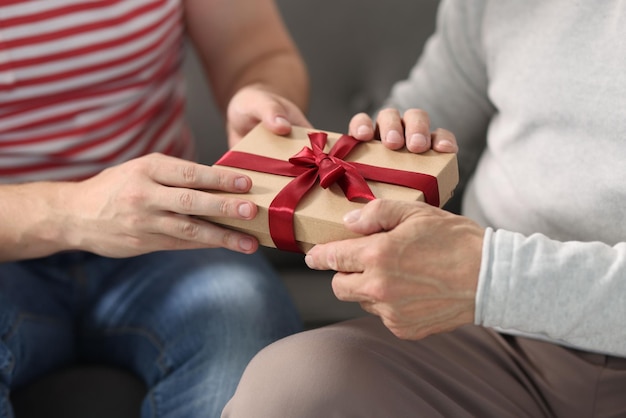 Fils donnant une boîte cadeau à son père sur le canapé en gros plan
