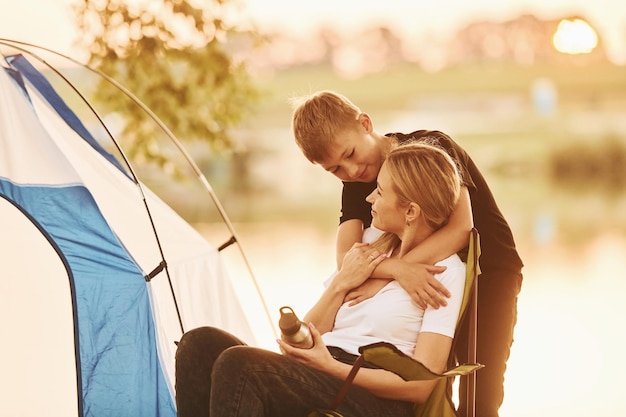 Fils embrassant sa mère près de la tente à l'extérieur