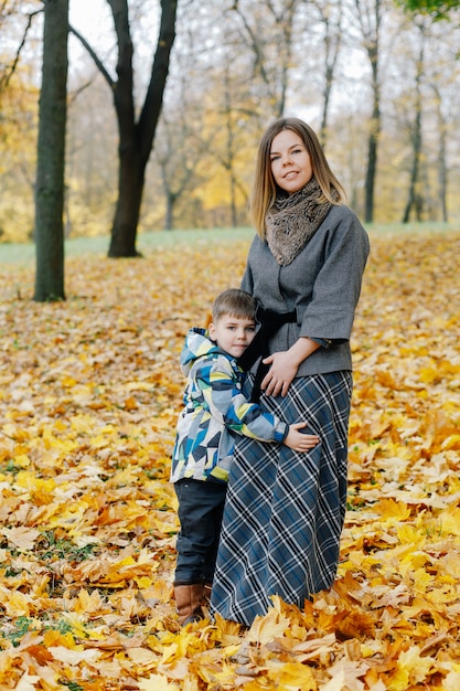 Photo fils embrasse la mère dans le parc en automne. maman et fils embrassant dans le parc en automne