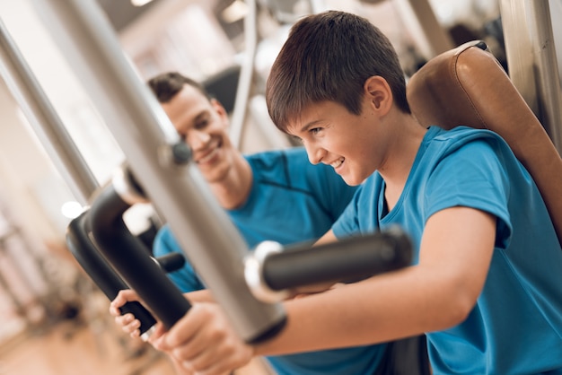 Le fils entraîne les muscles pectoraux pendant que papa regarde.